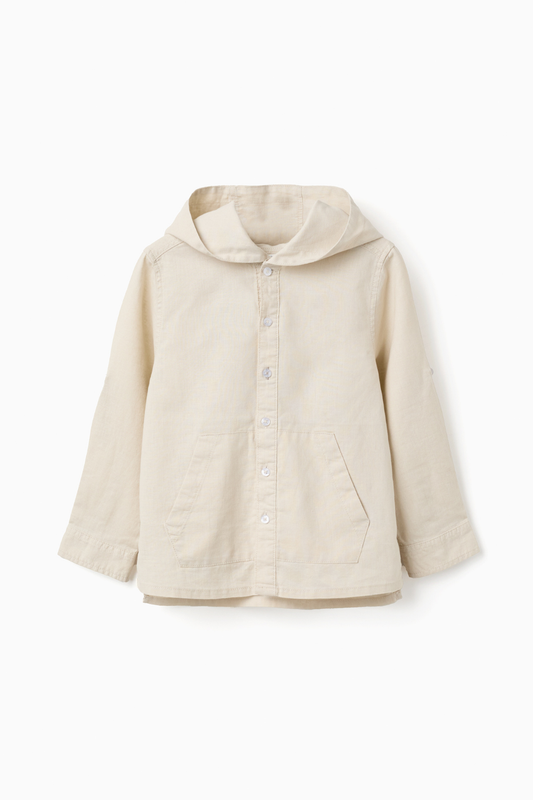 Camisa infantil beige con capucha, botones delanteros y bolsillos, ideal como chaqueta ligera para niño en entretiempo.