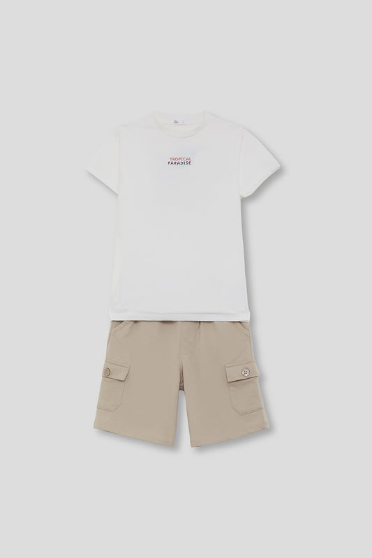 Conjunto infantil de verano compuesto por camiseta blanca con texto “Tropical Paradise” y bermuda beige estilo cargo con bolsillos laterales, sobre fondo neutro.