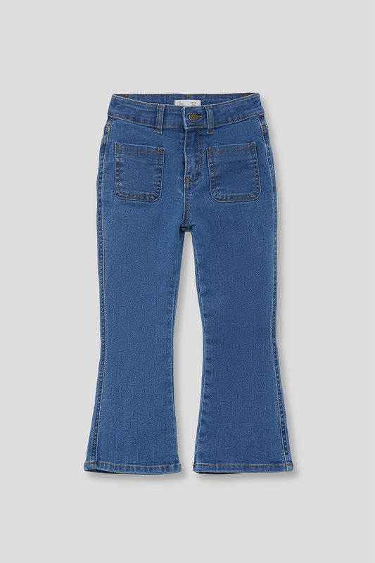 Pantalón infantil vaquero azul con corte acampanado y bolsillos delanteros de parche, sobre fondo neutro.