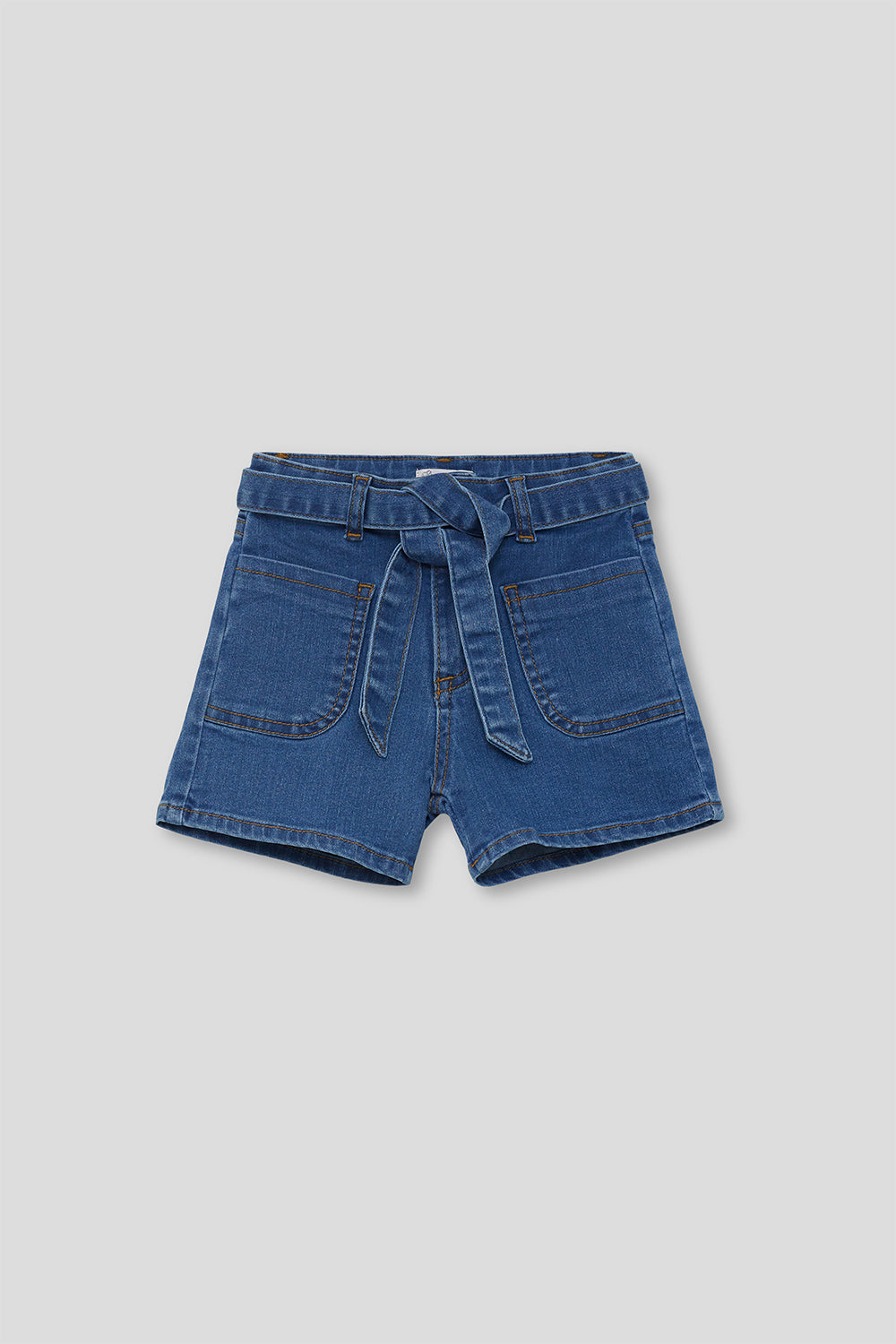 Short infantil vaquero azul con cinturón del mismo tejido anudado en la cintura y bolsillos delanteros amplios, sobre fondo neutro.