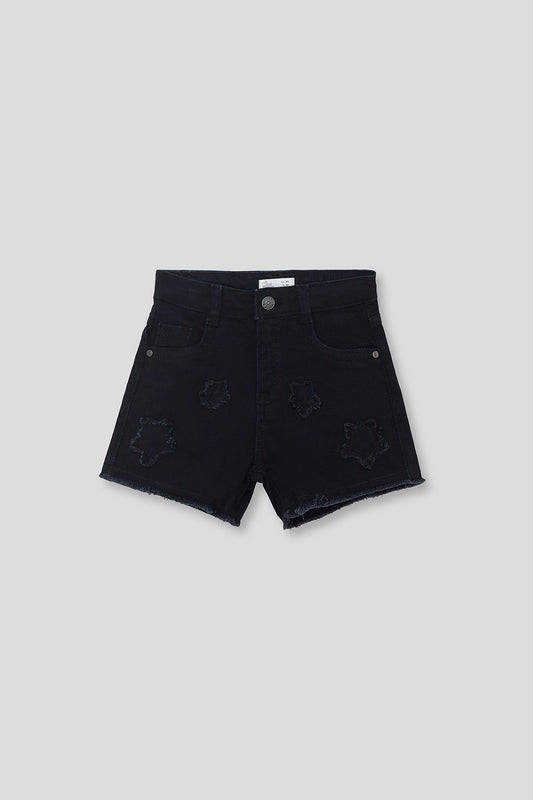 Short infantil vaquero negro con efecto desgastado y detalles de estrellas en relieve, con bajo deshilachado, sobre fondo neutro.

